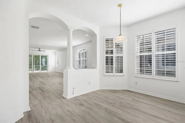 a view of empty room with wooden floor and fan