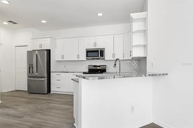a kitchen with granite countertop a refrigerator and a stove top oven