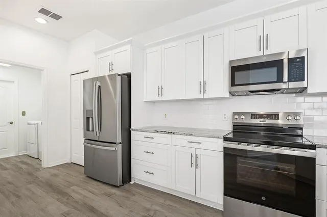 a kitchen with cabinets stainless steel appliances and wooden floor