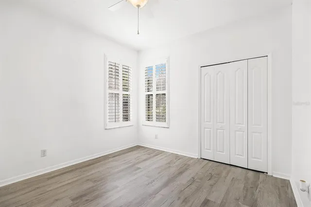 an empty room with wooden floor cabinet and windows
