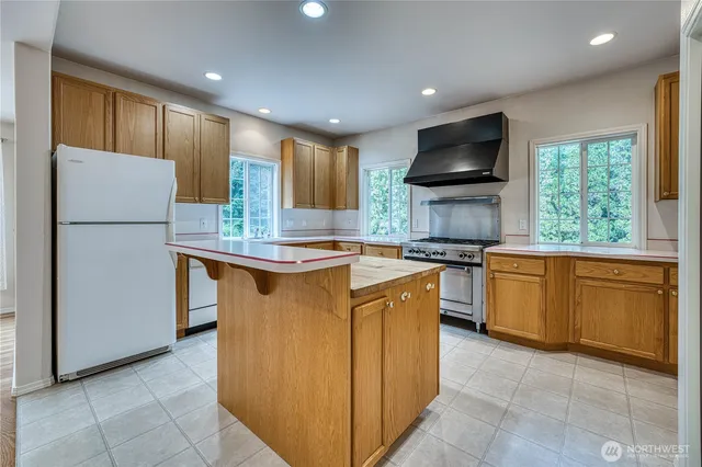 a kitchen with granite countertop a refrigerator a sink and a stove top oven