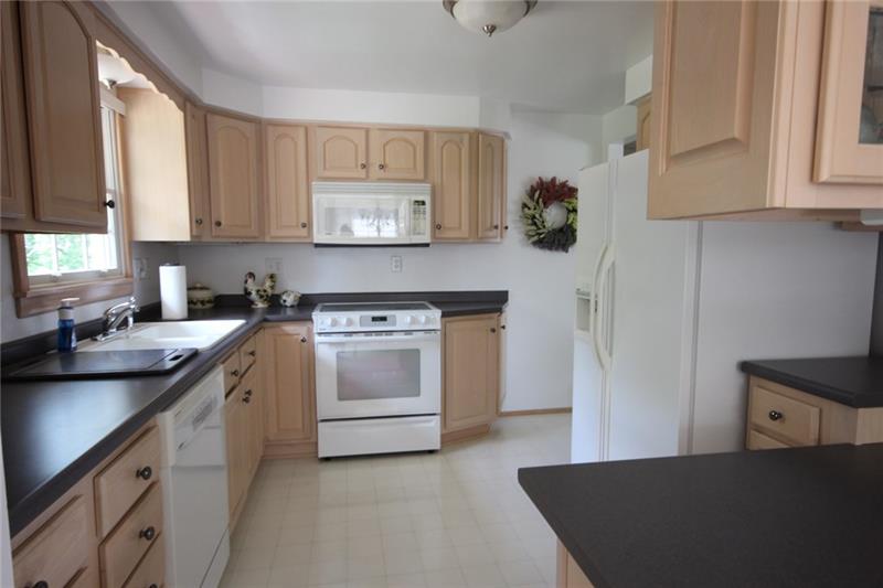 81 Observatory Street Manor, PA 15665 - Photo 10 of 25 Spotless kitchen features light cabinetry, breakfast bar and all appliances.