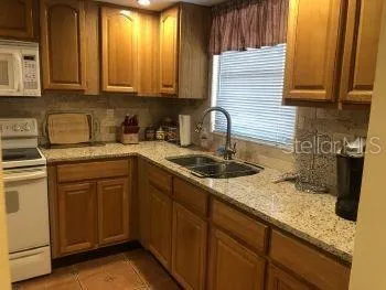 a kitchen with granite countertop a sink a stove and cabinets
