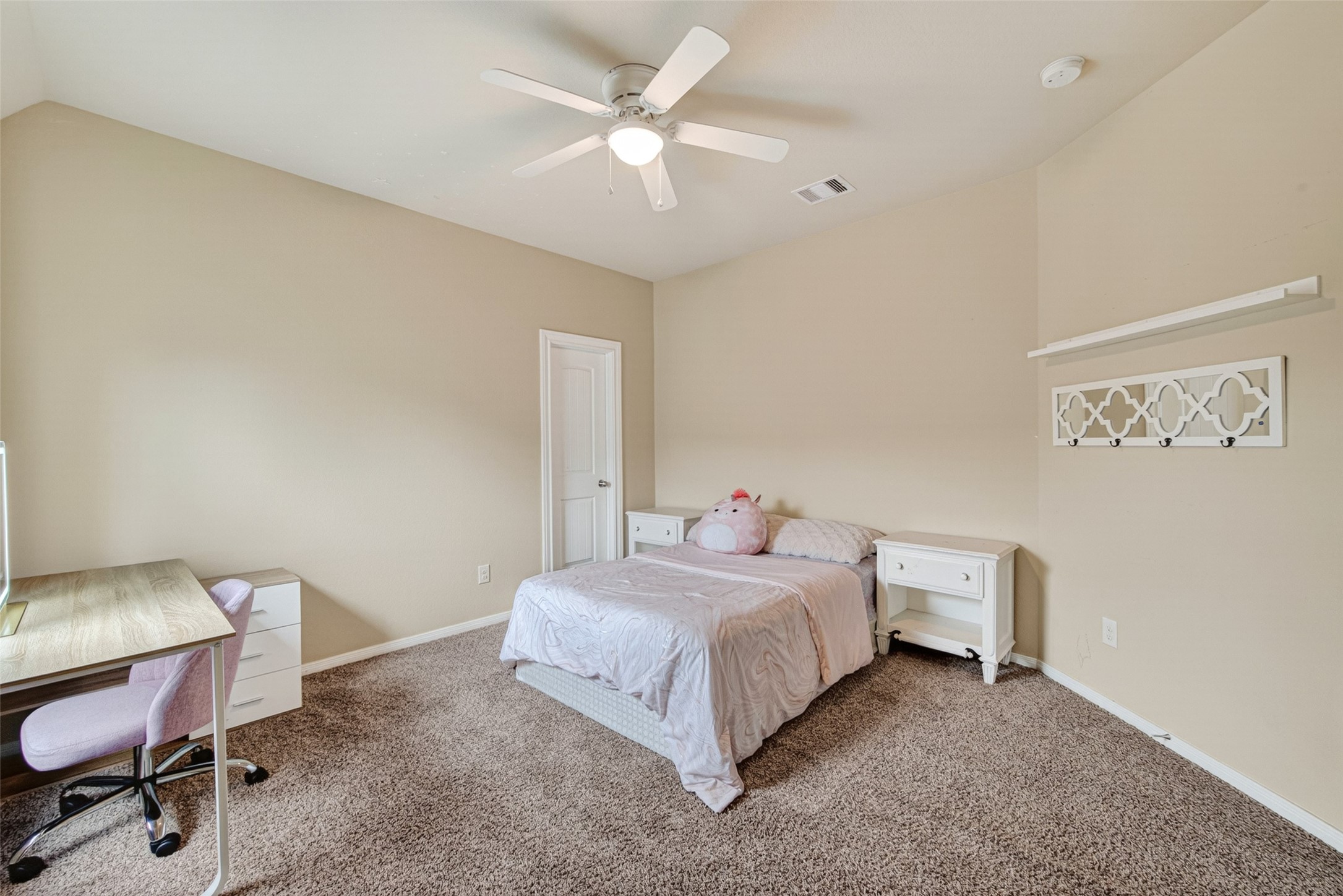 25611 Ellis Ridge Court Katy, TX 77494 - Photo 35 of 49 This is a cozy bedroom with neutral walls and carpeted flooring. It features a ceiling fan, a bed with side tables, a small desk with a chair, and a decorative wall shelf, offering a comfortable and functional space.