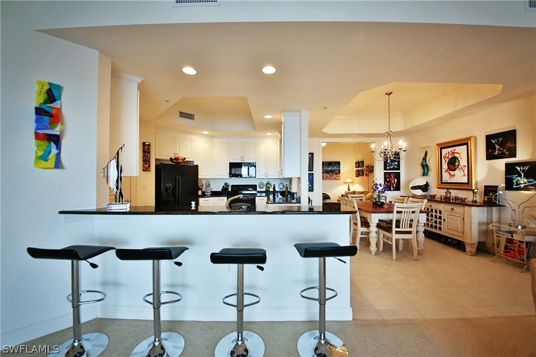 2090 West First Street, Unit 2107 Fort Myers, FL 33901 - Photo 19 of 35 a kitchen with a dining table chairs and white cabinets