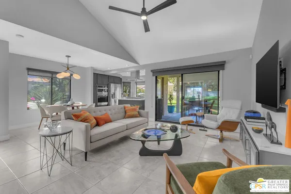 a living room with furniture a flat screen tv and a large window