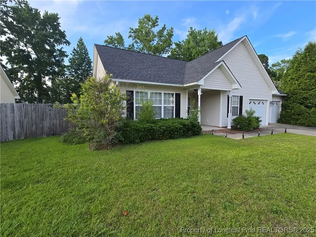 a front view of house with yard and trees in the background