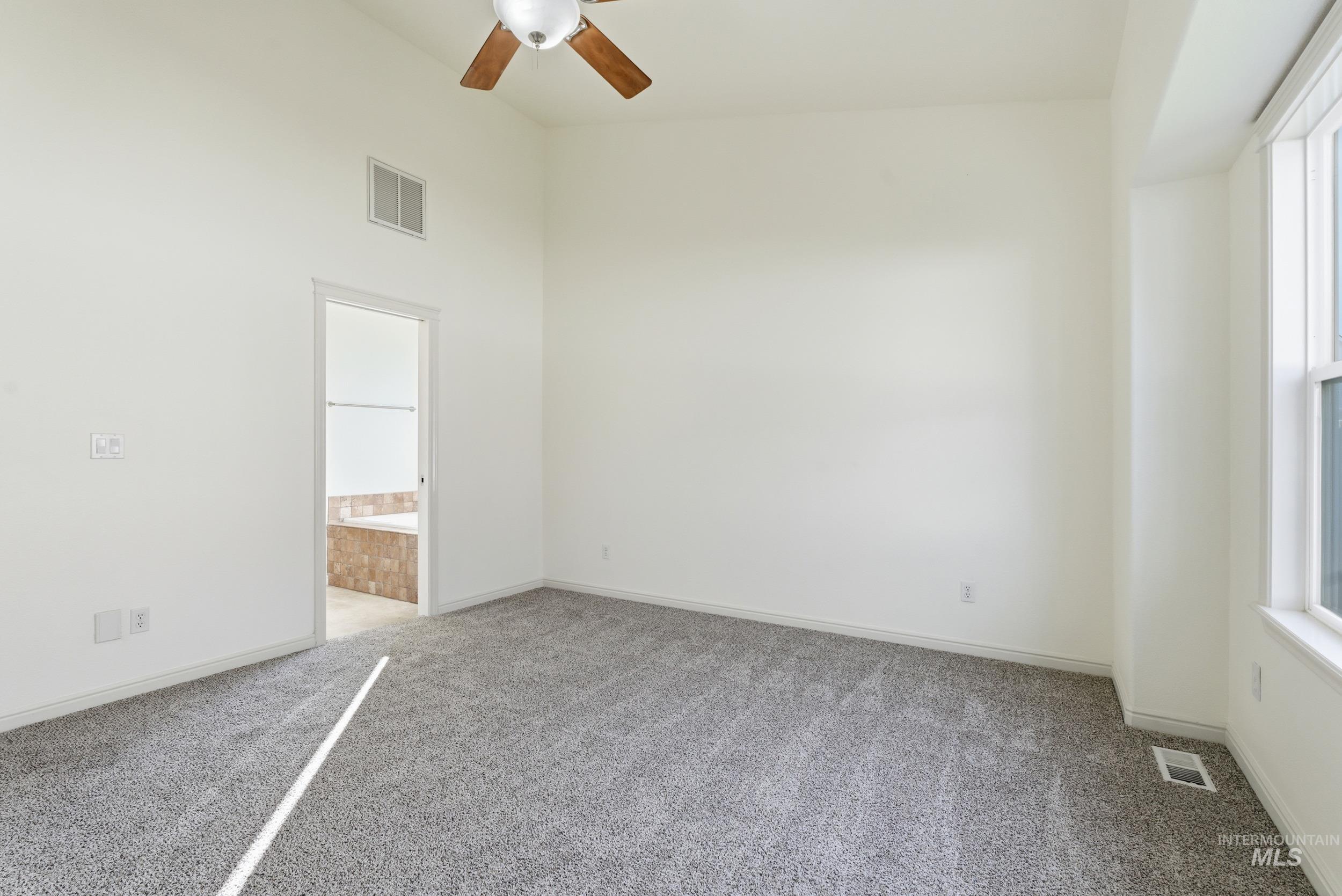 1133 North Powder River Drive Middleton, ID 83644 - Photo 13 of 33 Empty room featuring light carpet, a ceiling fan, and a towering ceiling