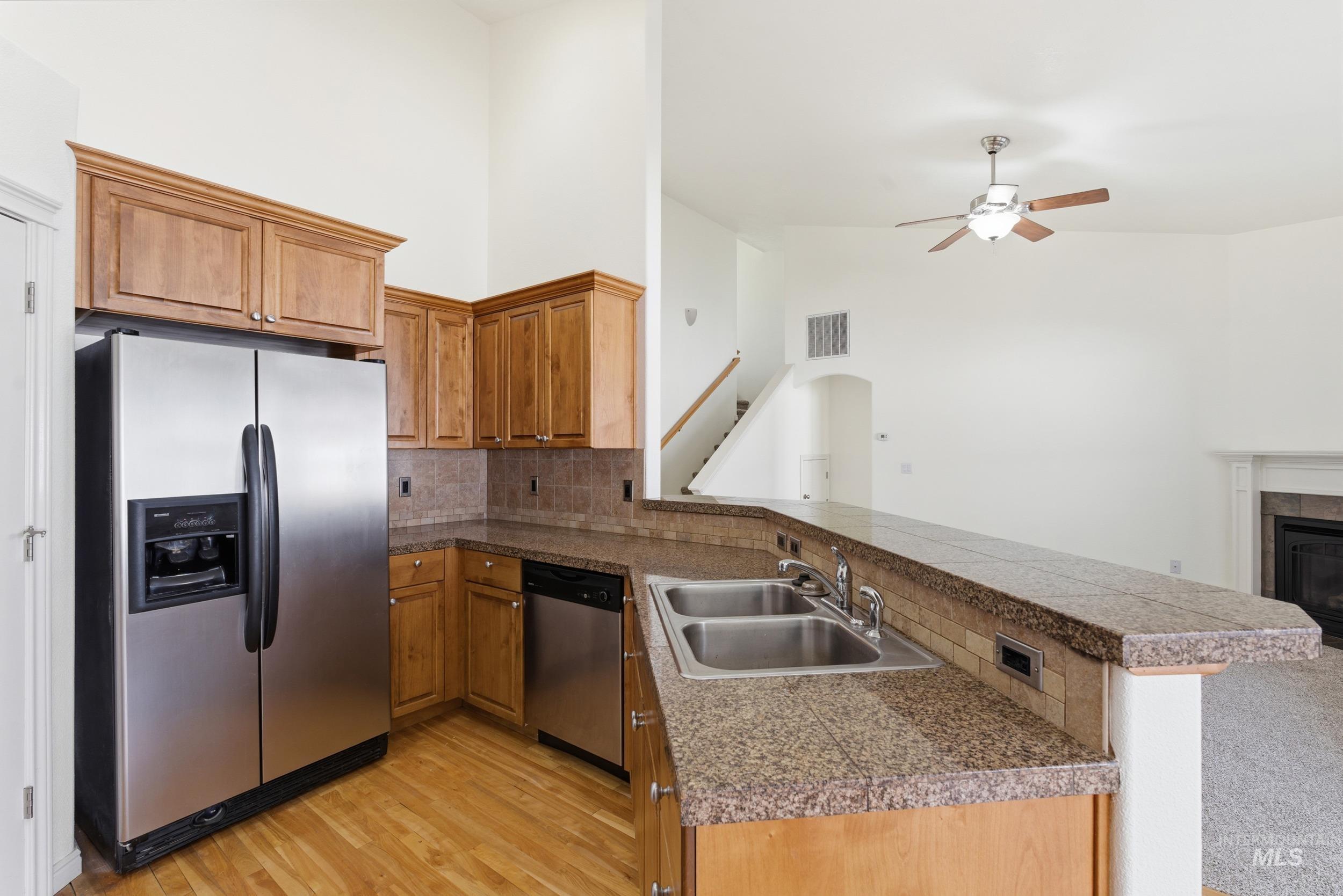 1133 North Powder River Drive Middleton, ID 83644 - Photo 33 of 33 Kitchen with a peninsula, appliances with stainless steel finishes, brown cabinetry, tile countertops, and open floor plan