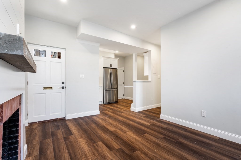 31 Monadnock Street, Unit 2 Boston, MA 02125 - Photo 3 of 11 a view of an empty room with wooden floor and a fireplace