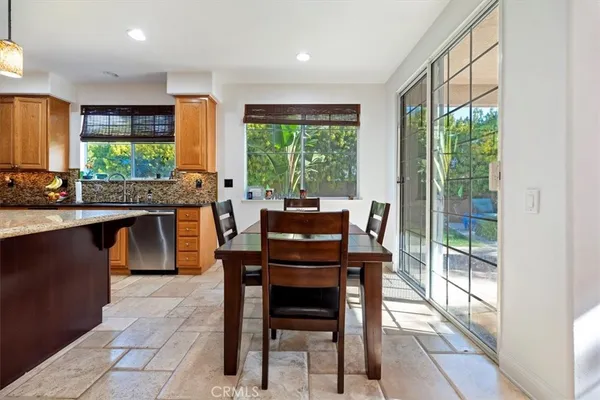 a kitchen with stainless steel appliances granite countertop a stove top oven a sink a table and chairs