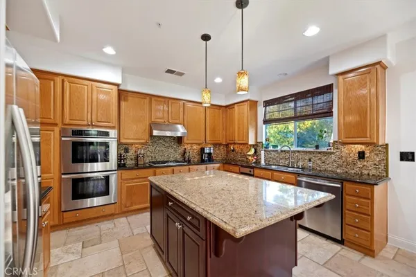 a kitchen with stainless steel appliances granite countertop a sink a stove and a refrigerator