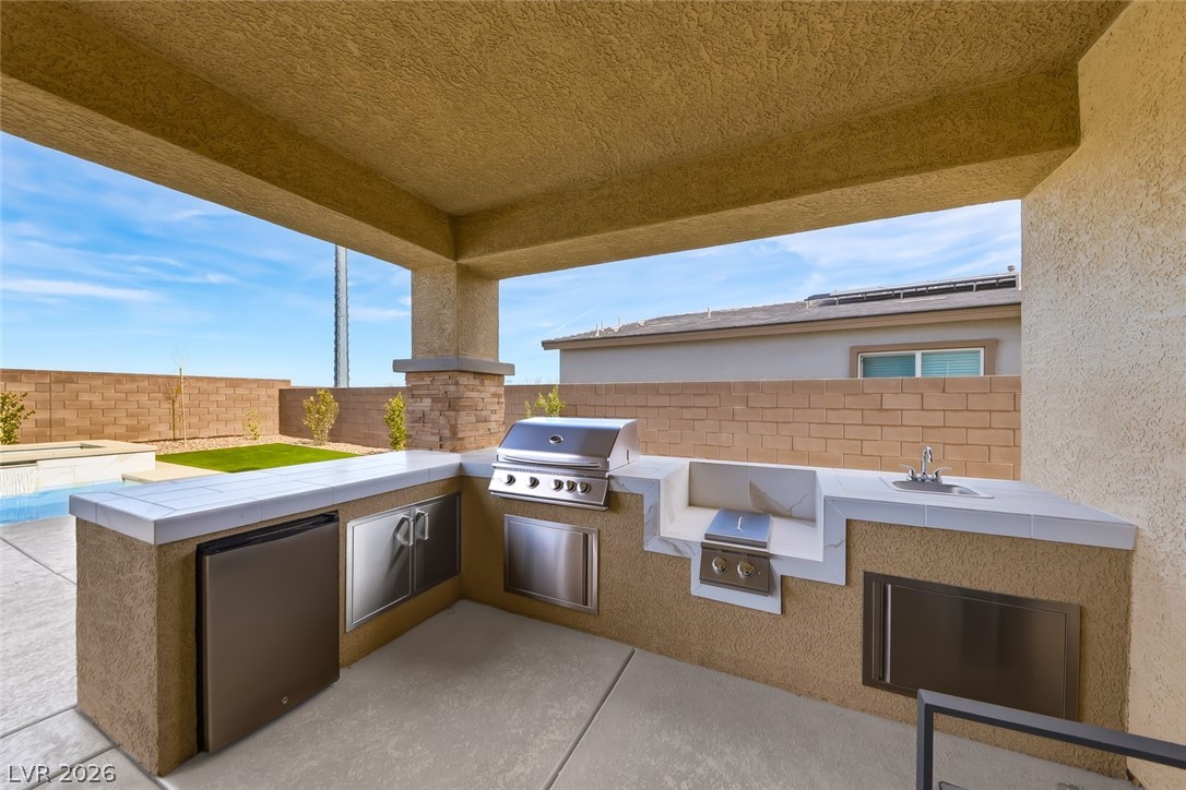 290 Rusty Ridge Lane Henderson, NV 89015 - Photo 44 of 61 Backyard w/pool & spa, desert rock w/synethic grass & pavers, built in outdoor kitchen w/fridge, cooktop & sink & No Rear Neighbors.