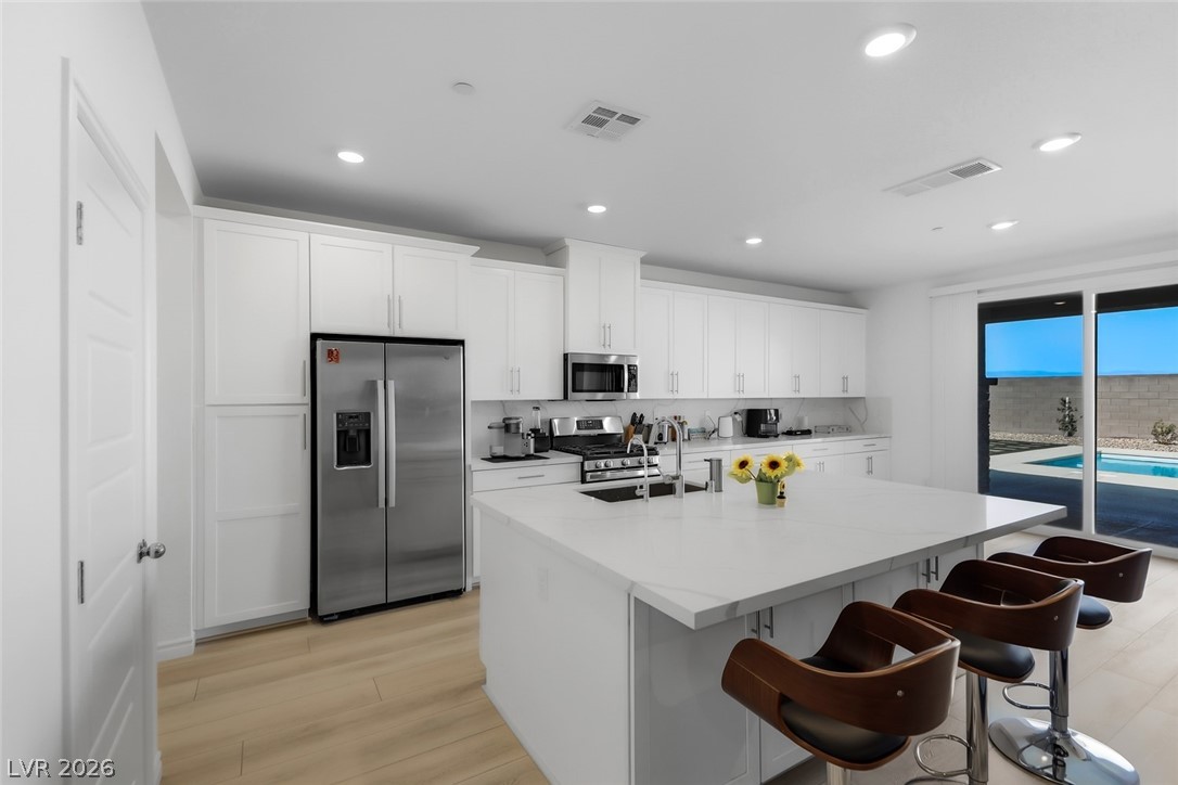 290 Rusty Ridge Lane Henderson, NV 89015 - Photo 7 of 61 Kitchen w/White Shaker Cabinets, Island w/Breakfast Bar, Quartz Countertops, Luxury Vinyl floors, SS Appliances, walk in pantry, dining nook w/abundant cabinet space!
