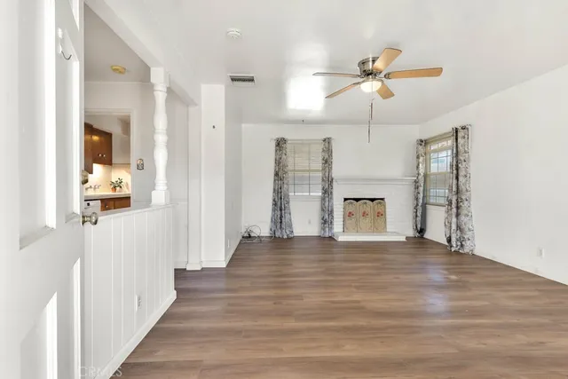 a view of a hallway with wooden floor and a ceiling fan