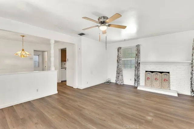 a view of empty room with wooden floor and ceiling fan