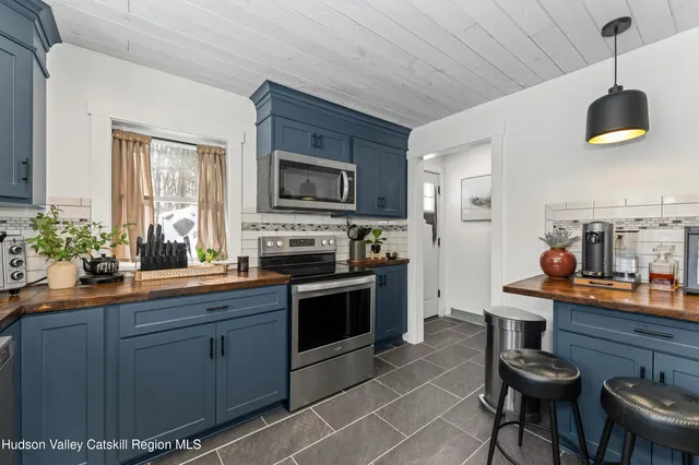 a kitchen with stainless steel appliances a stove a sink dishwasher a dining table and chairs with wooden floor