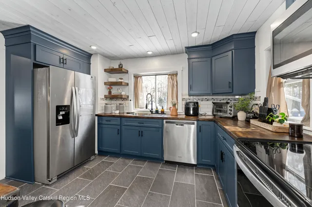 a kitchen with stainless steel appliances granite countertop a refrigerator a sink dishwasher a stove and white countertops with wooden floor