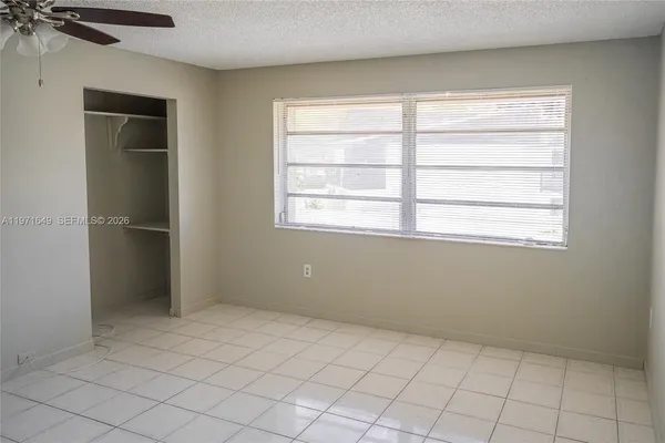 an empty room with chandelier fan and windows