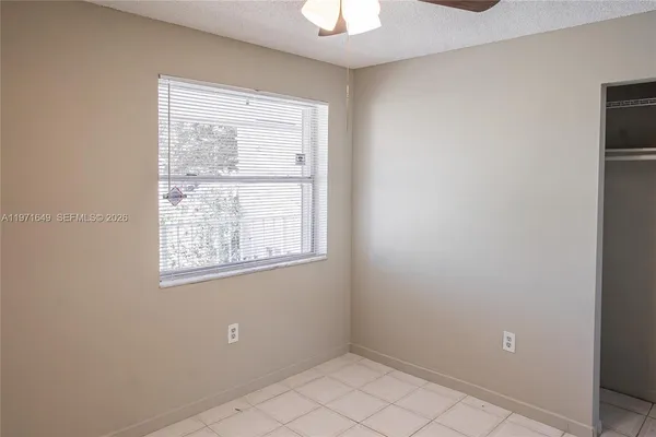 a view of an empty room with chandelier fan