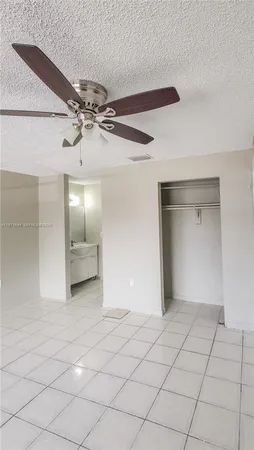 a view of an empty room and chandelier fan