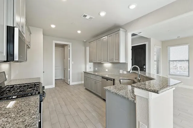 a kitchen with stainless steel appliances granite countertop wooden cabinets a stove top oven a sink and dishwasher