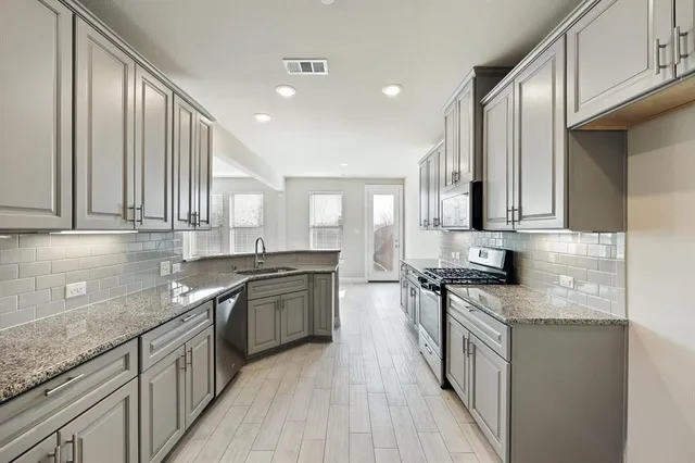 a kitchen with stainless steel appliances granite countertop a sink stove and cabinets