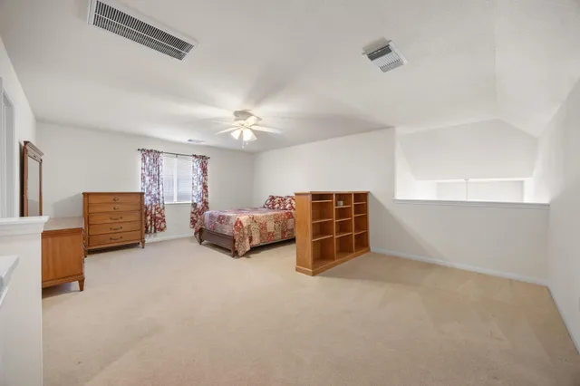 a bedroom with a large bed and a chandelier fan