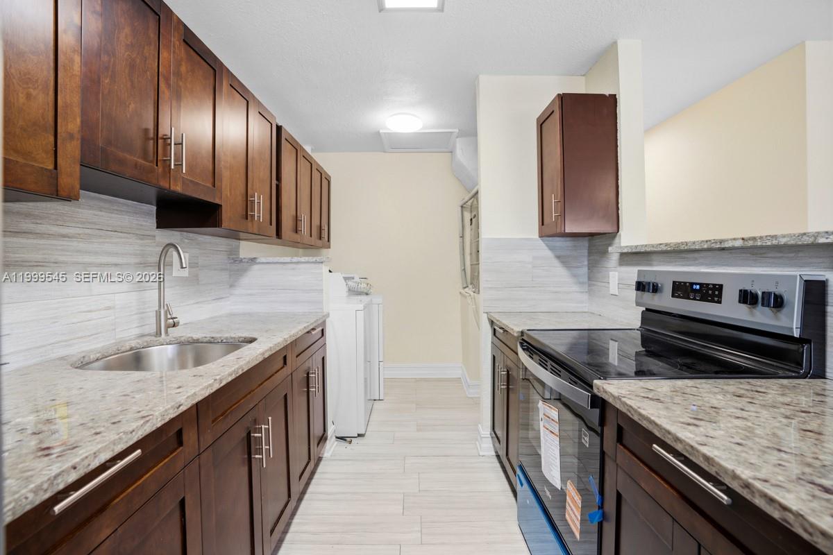 7604 Southwest 10th Court, Unit 2 Pompano Beach, FL 33068 - Photo 2 of 19 a kitchen with granite countertop stainless steel appliances a sink a stove and a wooden cabinets