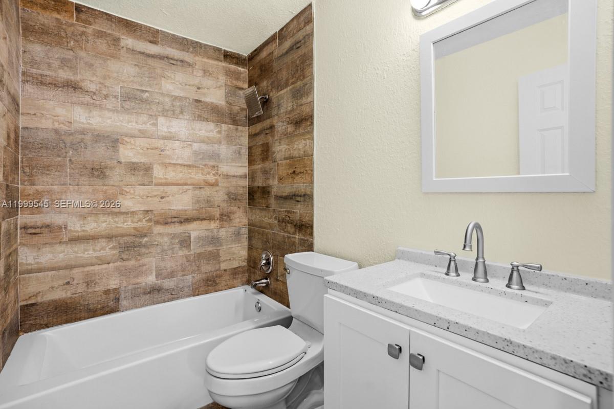 7604 Southwest 10th Court, Unit 2 Pompano Beach, FL 33068 - Photo 9 of 19 a bathroom with a granite countertop sink a toilet and bathtub