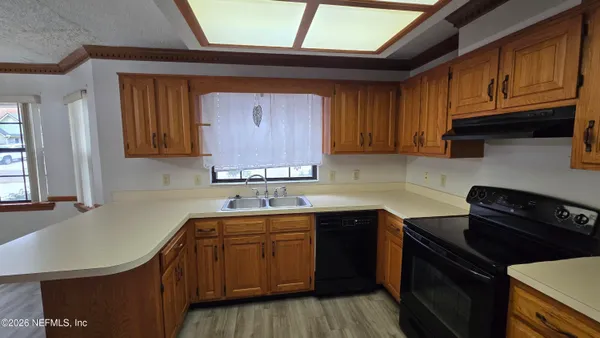 a large kitchen with stainless steel appliances granite countertop a stove a refrigerator a sink dishwasher and wooden cabinets with wooden floor