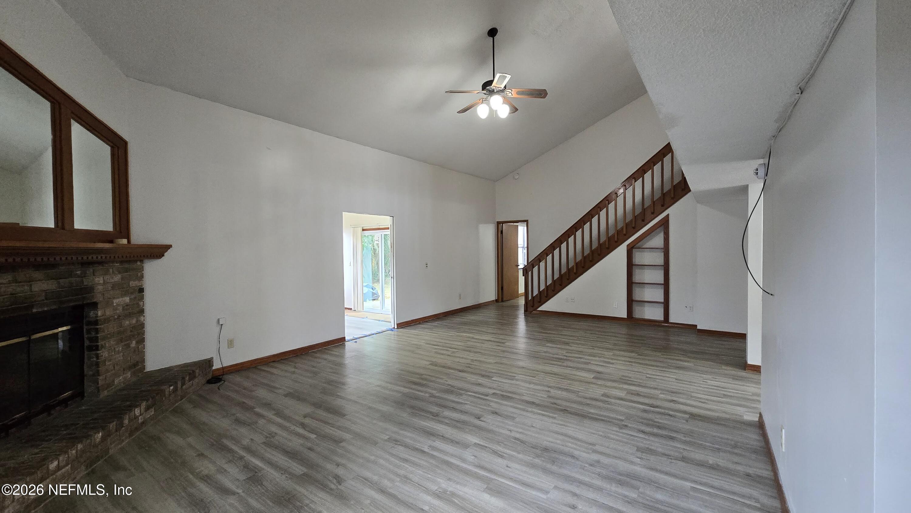 8532 Bandera Circle East Jacksonville, FL 32244 - Photo 15 of 47 an empty room with wooden floor staircase and a fireplace