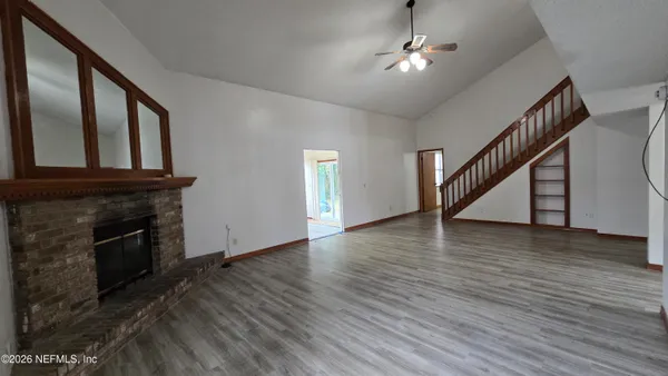 an empty room with wooden floor staircase and a fireplace