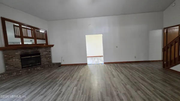 a view of empty room with wooden floor fireplace and a window