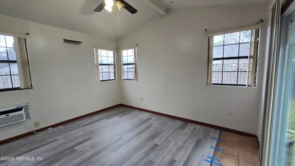 an empty room with wooden floor chandelier fan and windows