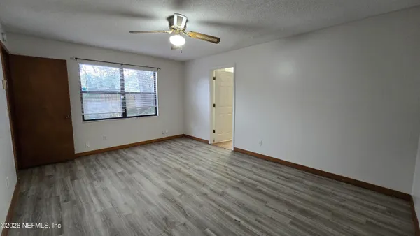 a view of an empty room with wooden floor and a window