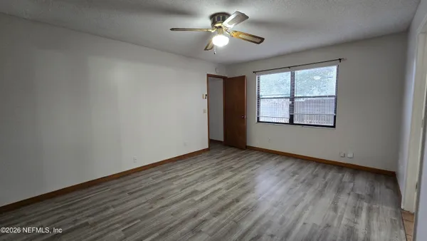 an empty room with wooden floor chandelier fan and windows