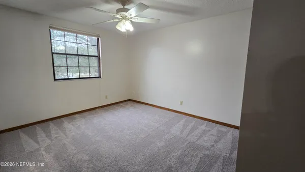 an empty room with windows and chandelier fan