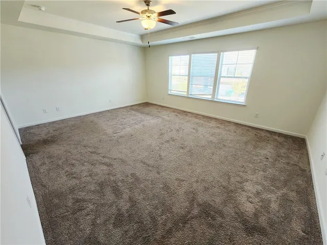 an empty room with windows and chandelier fan