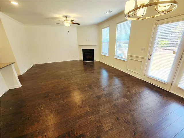a view of a livingroom with a fireplace a ceiling fan and wooden floor