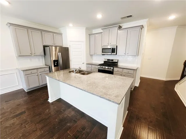 a kitchen with stainless steel appliances a refrigerator a sink a stove a microwave and wooden floor