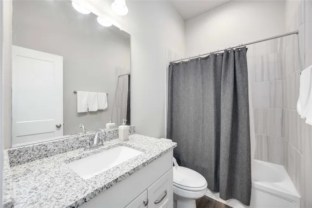 a bathroom with a granite countertop sink toilet and shower