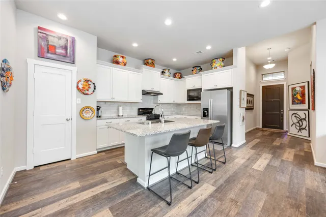 a kitchen with stainless steel appliances kitchen island granite countertop a refrigerator and a sink