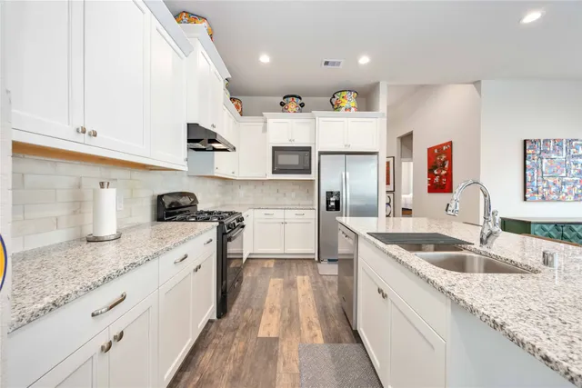 a large kitchen with stainless steel appliances granite countertop a sink stove and refrigerator