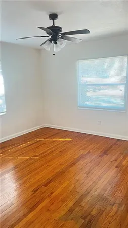 a view of a room with wooden floor fan and windows
