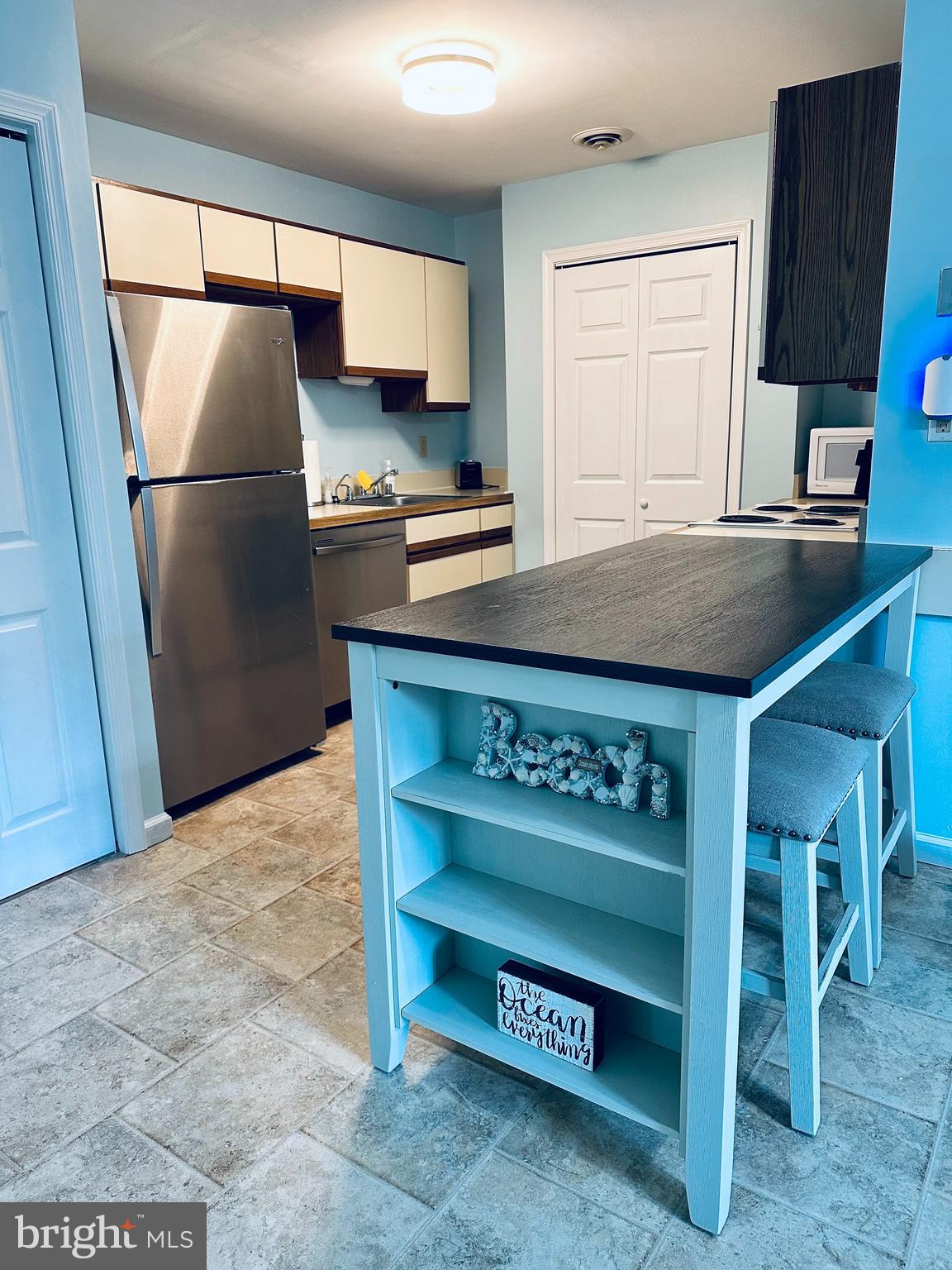 105 120th Street, Unit 84 Ocean City, MD 21842 - Photo 6 of 15 a kitchen with stainless steel appliances granite countertop a refrigerator a stove and a sink with wooden cabinets