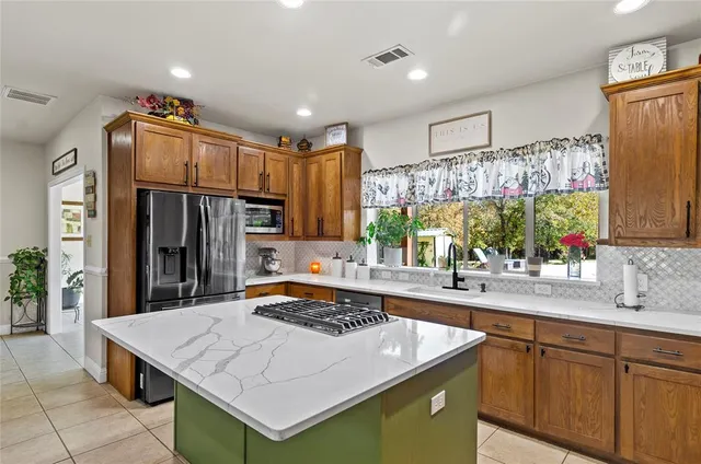 a kitchen with kitchen island granite countertop a sink stainless steel appliances and cabinets