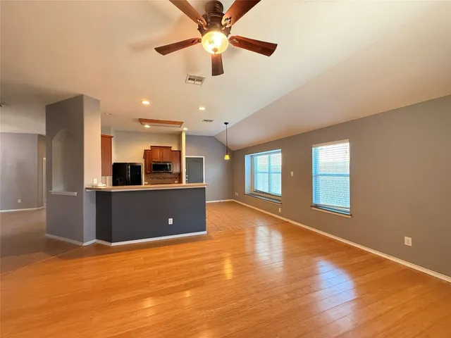 a view of an empty room with window and wooden floor