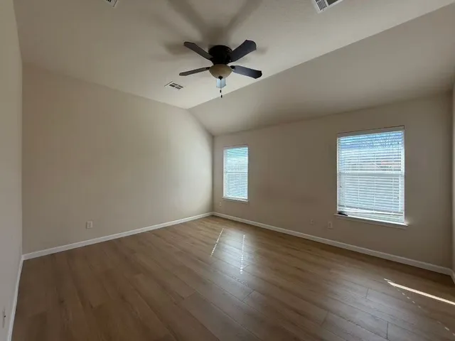 a view of an empty room with window and wooden floor