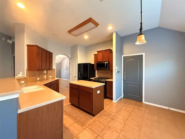 a kitchen with stainless steel appliances kitchen island a stove and a sink